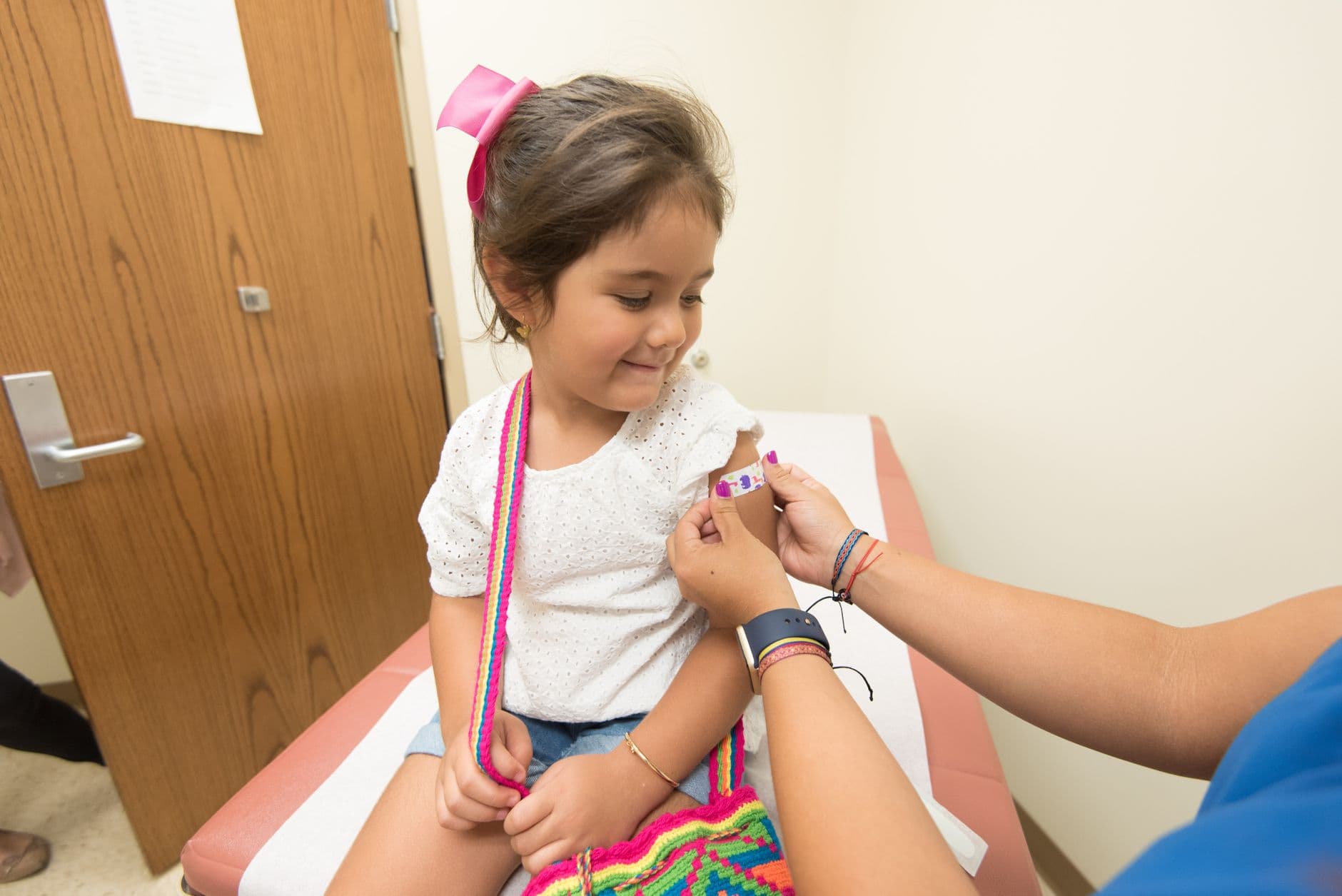 A cheerful young girl receives a band-aid after a vaccination at a clinic