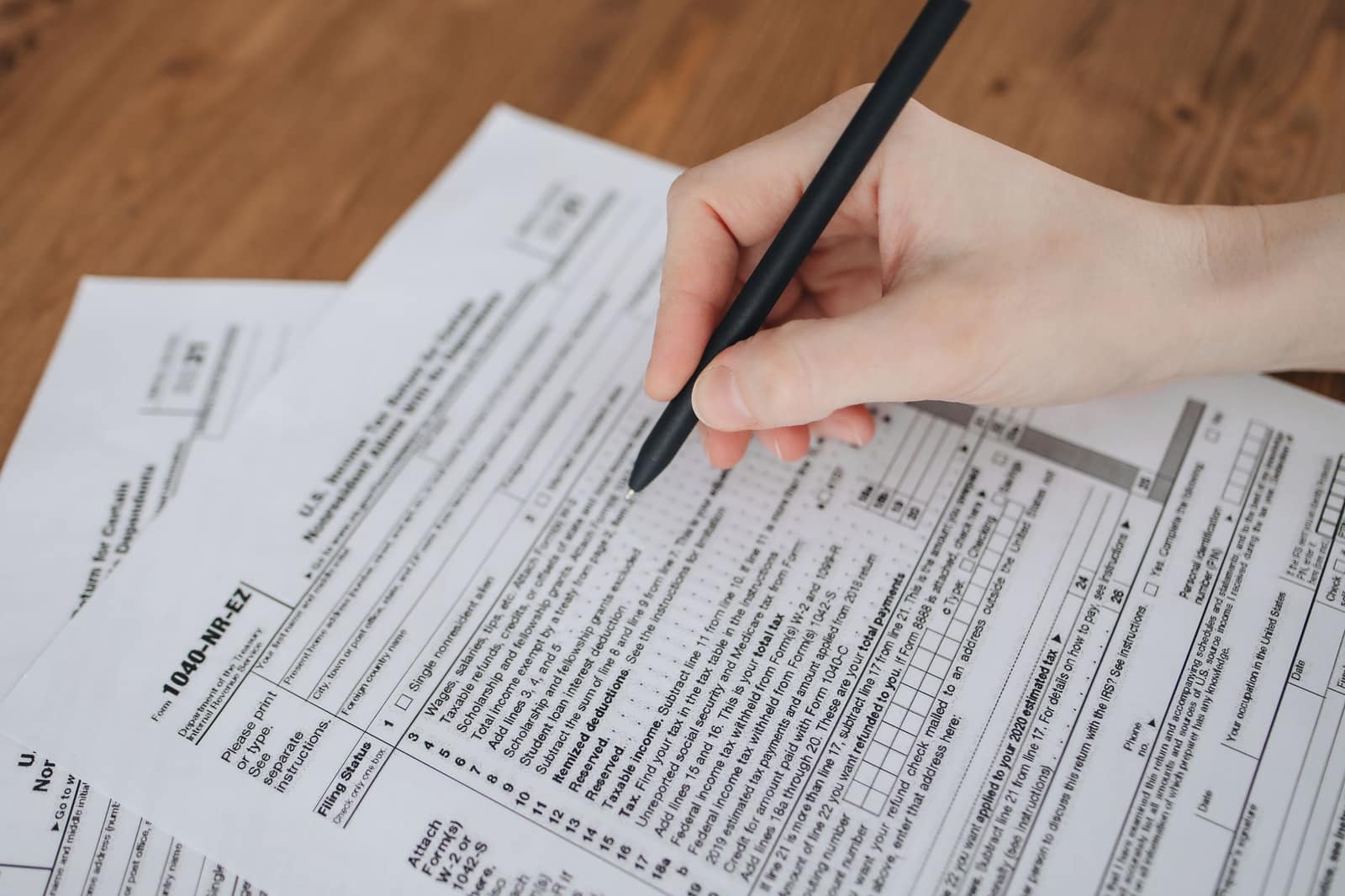 Close-up of a hand writing on an official paper form with a pen