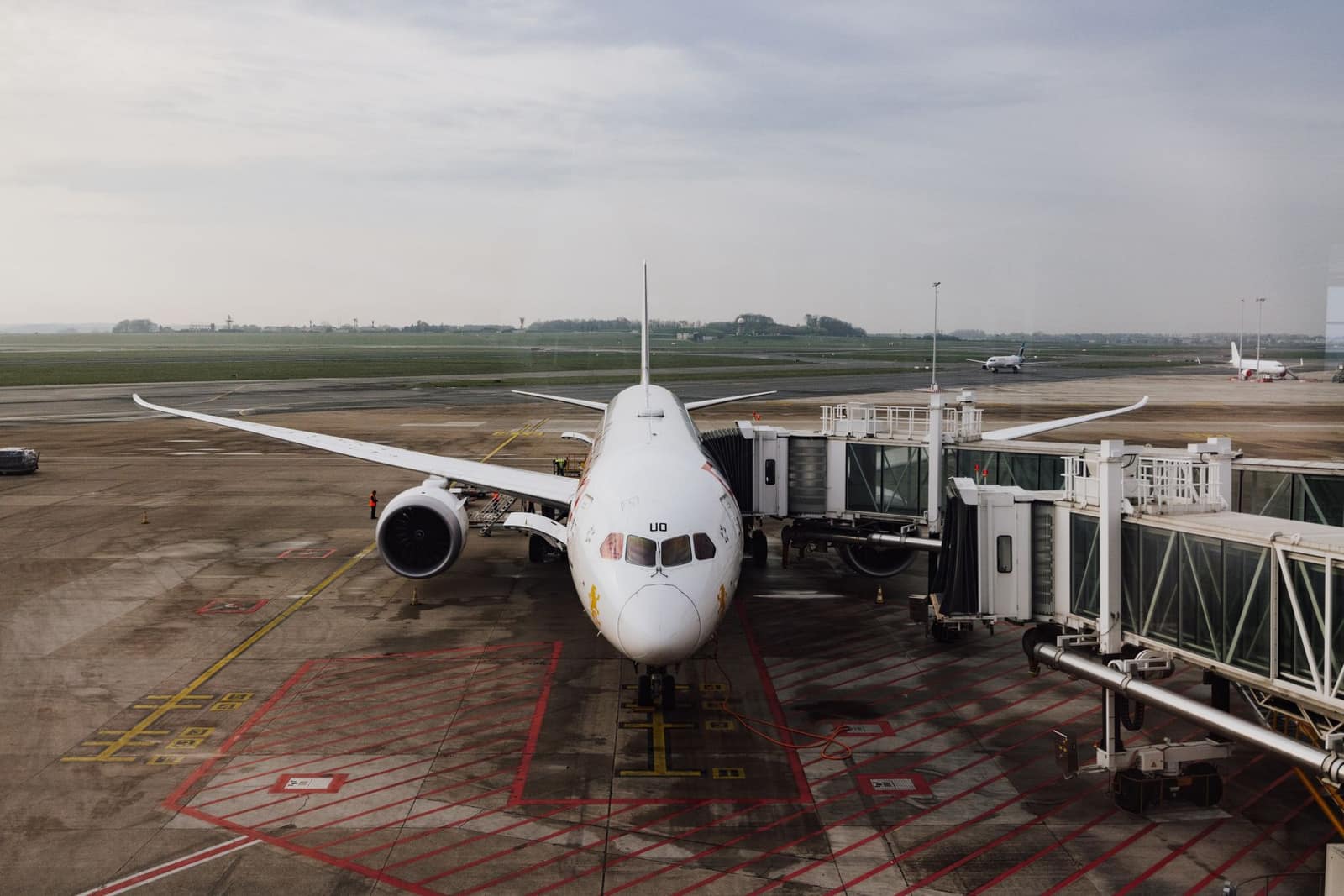 A modern jet airplane docked at an airport terminal gate on a cloudy day