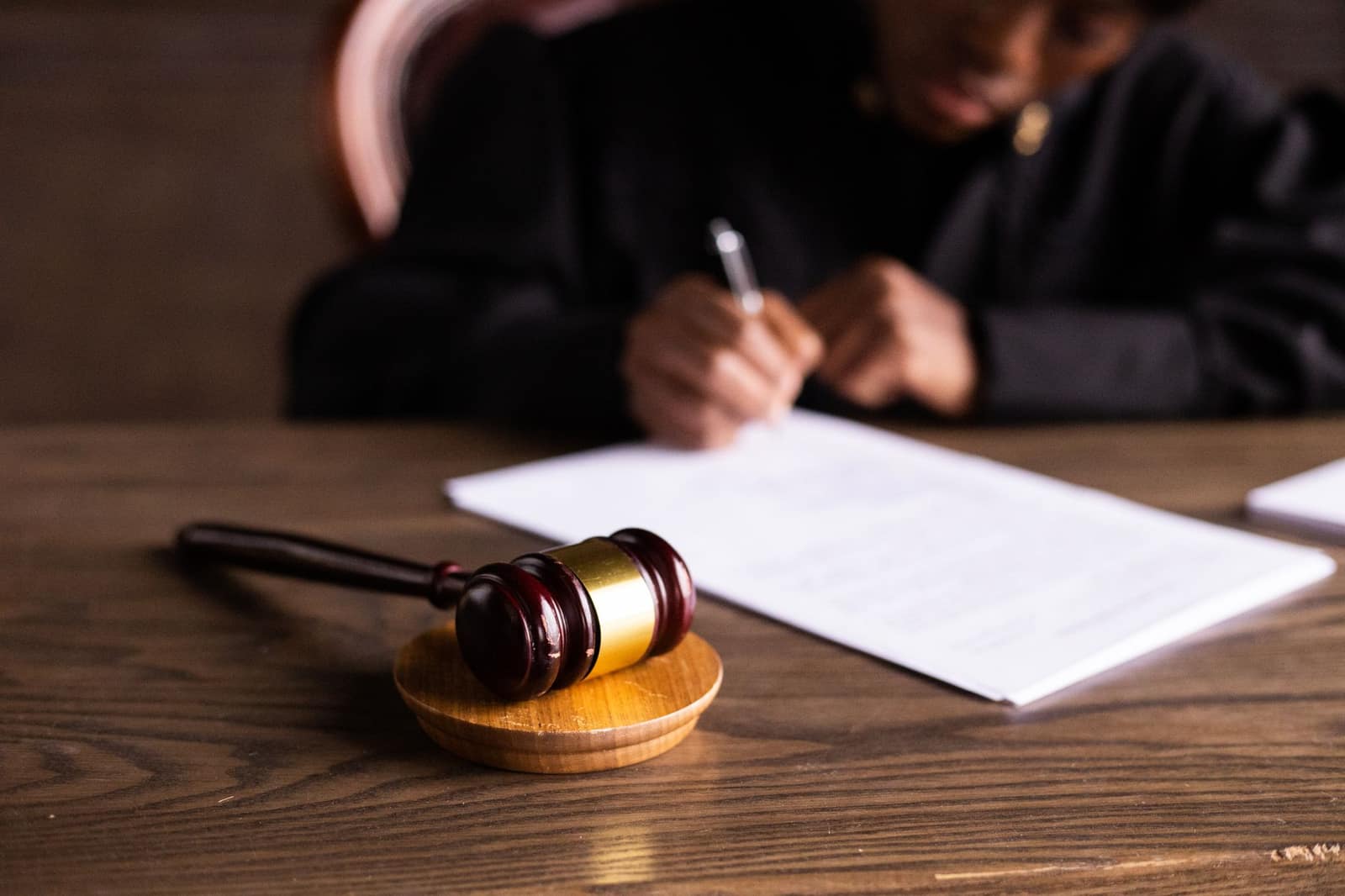 A judge signing documents at a desk with a gavel in the foreground