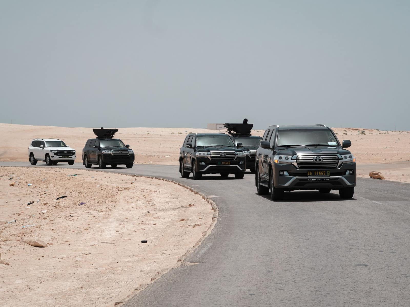 A convoy of armored vehicles traveling along a desert road