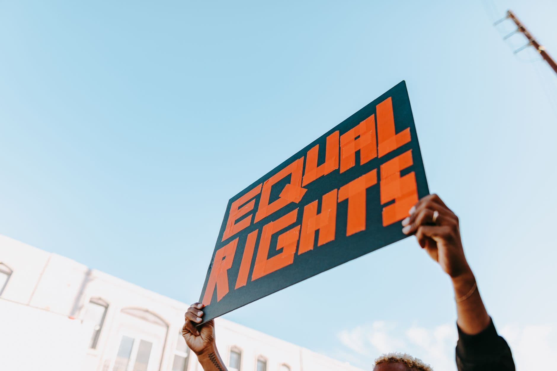 Hands holding a bold equal rights sign at an outdoor protest
