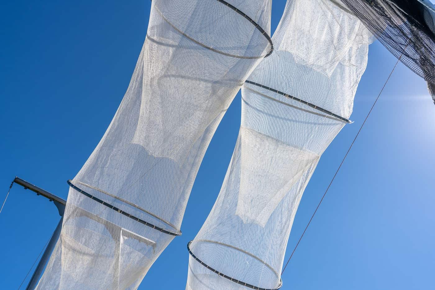 White fishing nets hanging under a bright blue sky, catching the sunlight