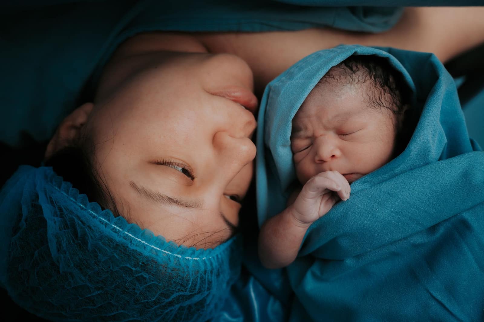 A mother holding her newborn baby wrapped in a hospital blanket