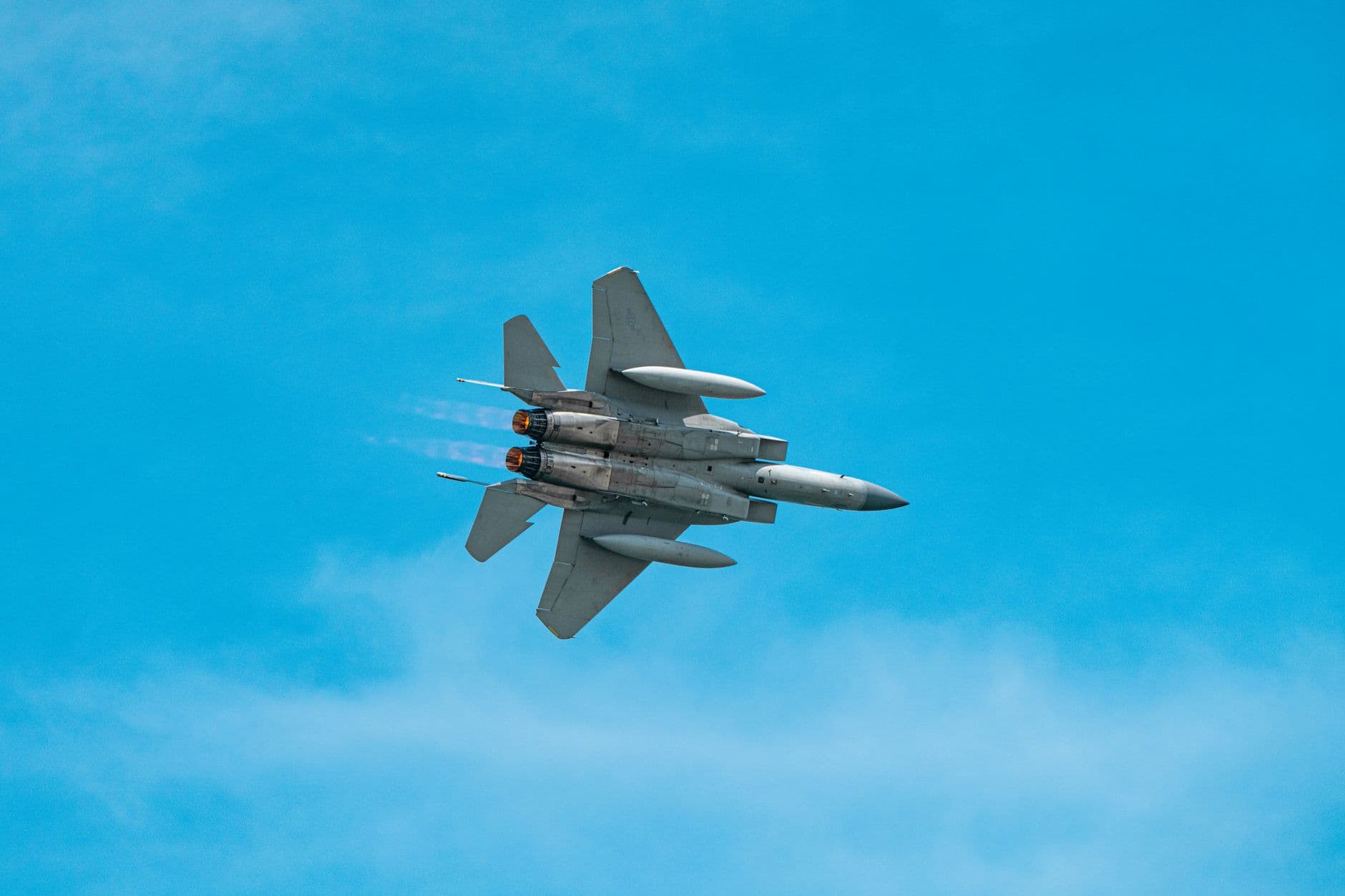 A military jet aircraft soaring through a clear blue sky