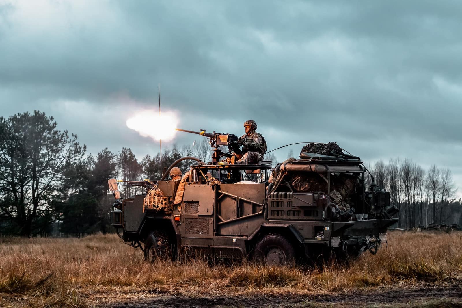 A soldier operating a mounted weapon on a military vehicle during an outdoor exercise