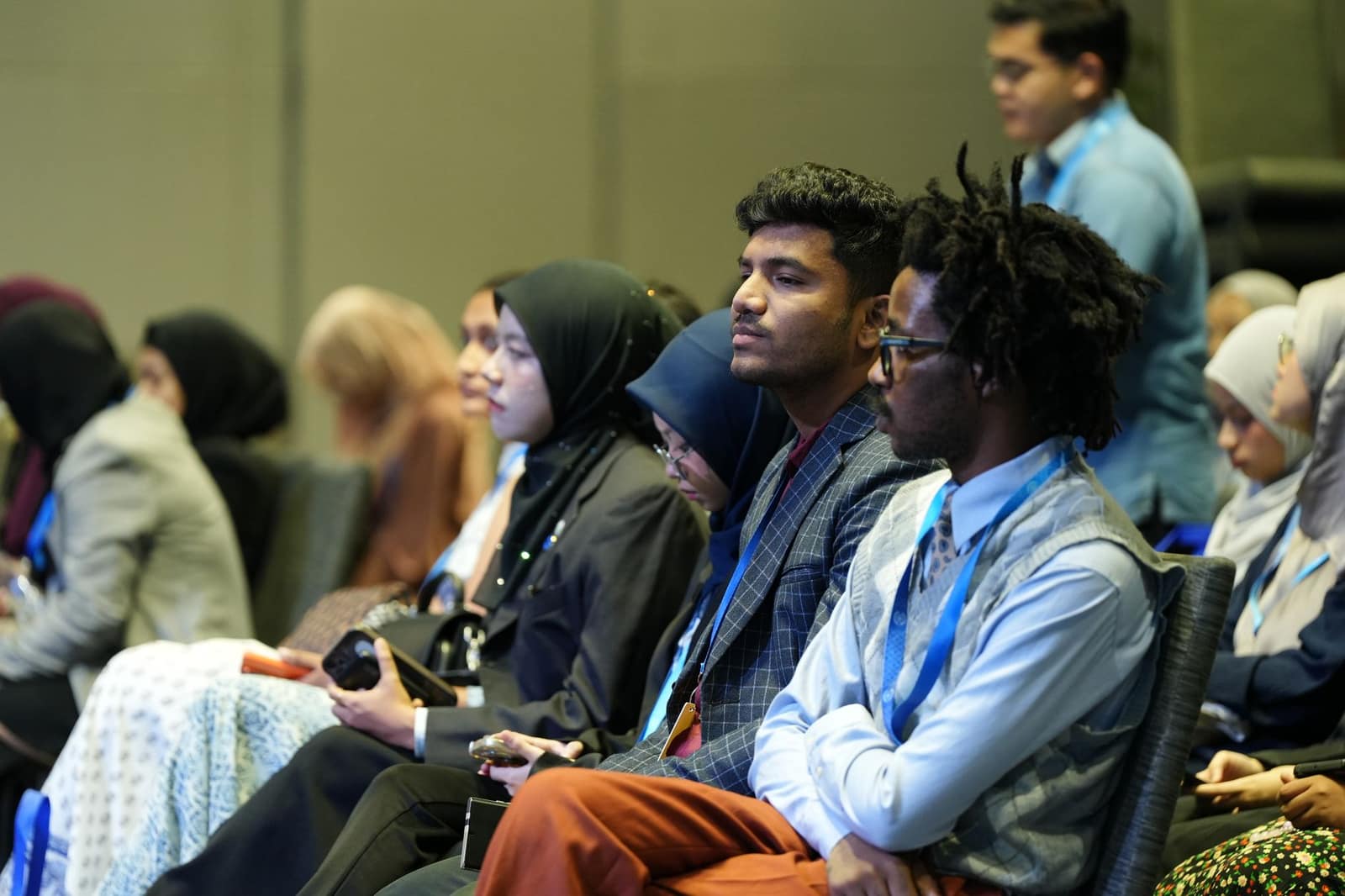 Attendees seated at rows of desks in a large conference hall