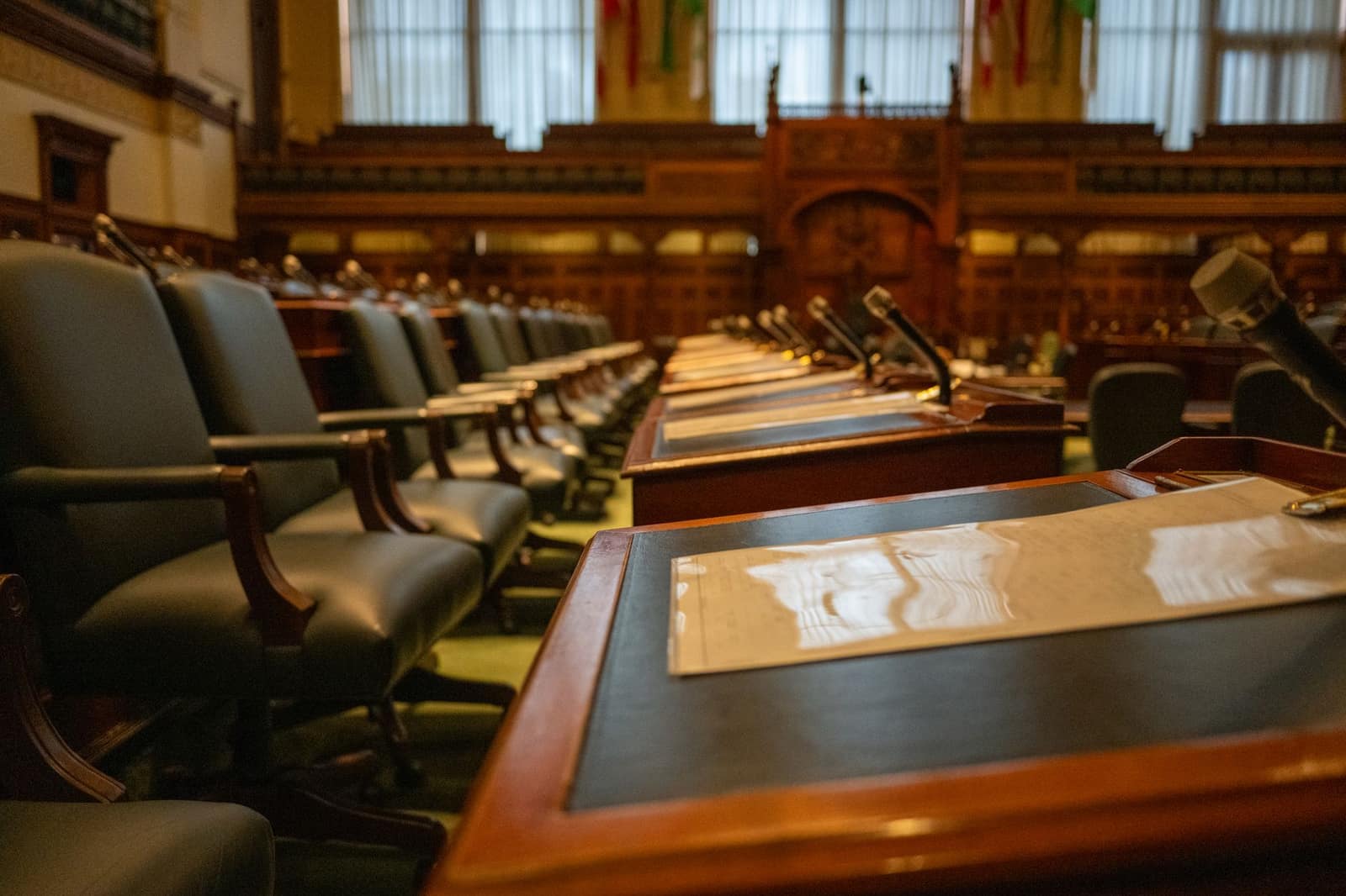 Empty legislative assembly chamber with rows of desks and microphones