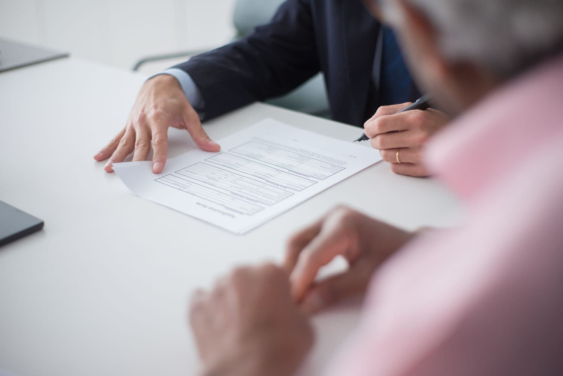 Two professionals shaking hands and signing documents during a business meeting
