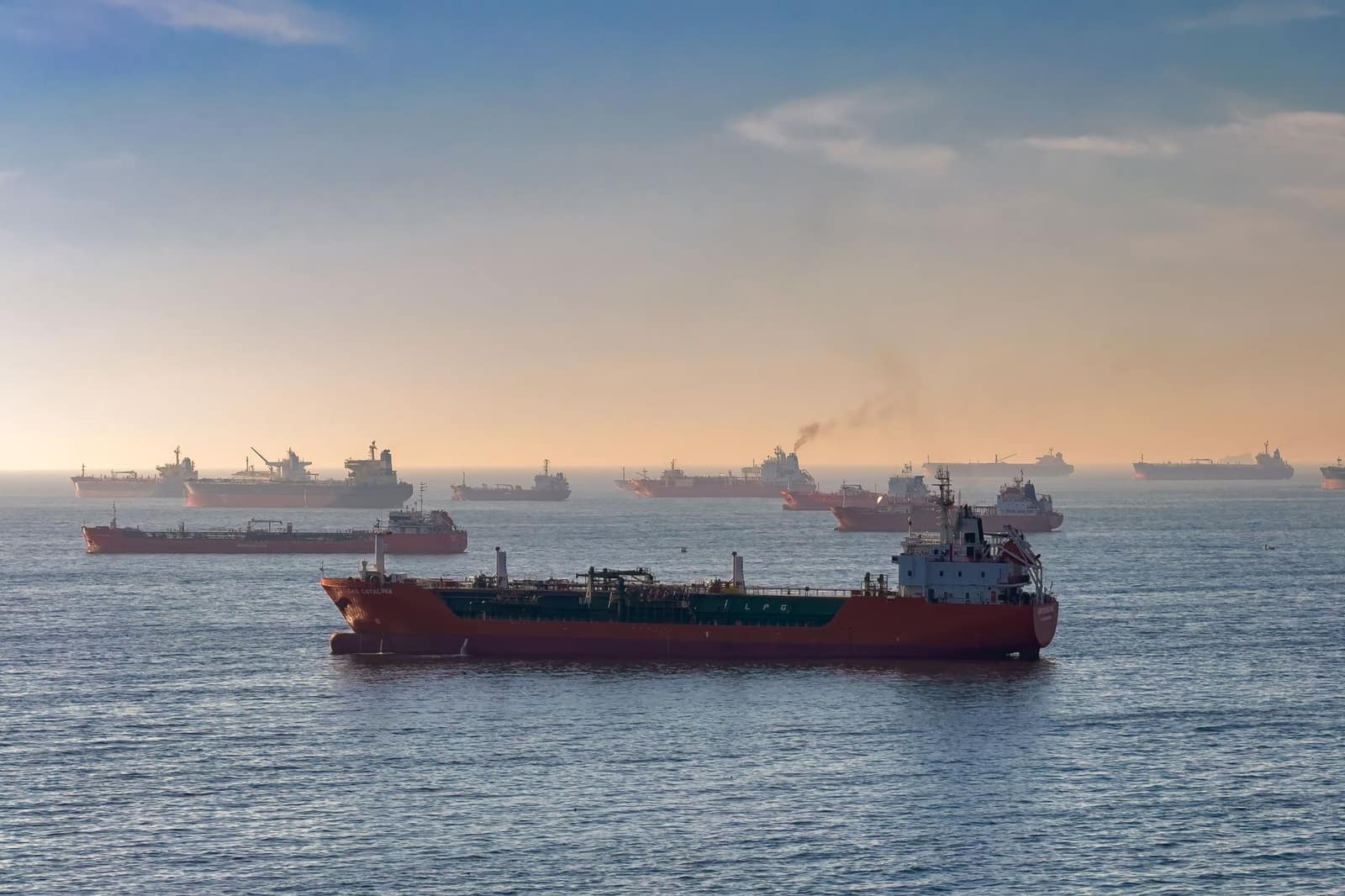 Oil tankers and cargo ships navigating a shipping strait at sunset