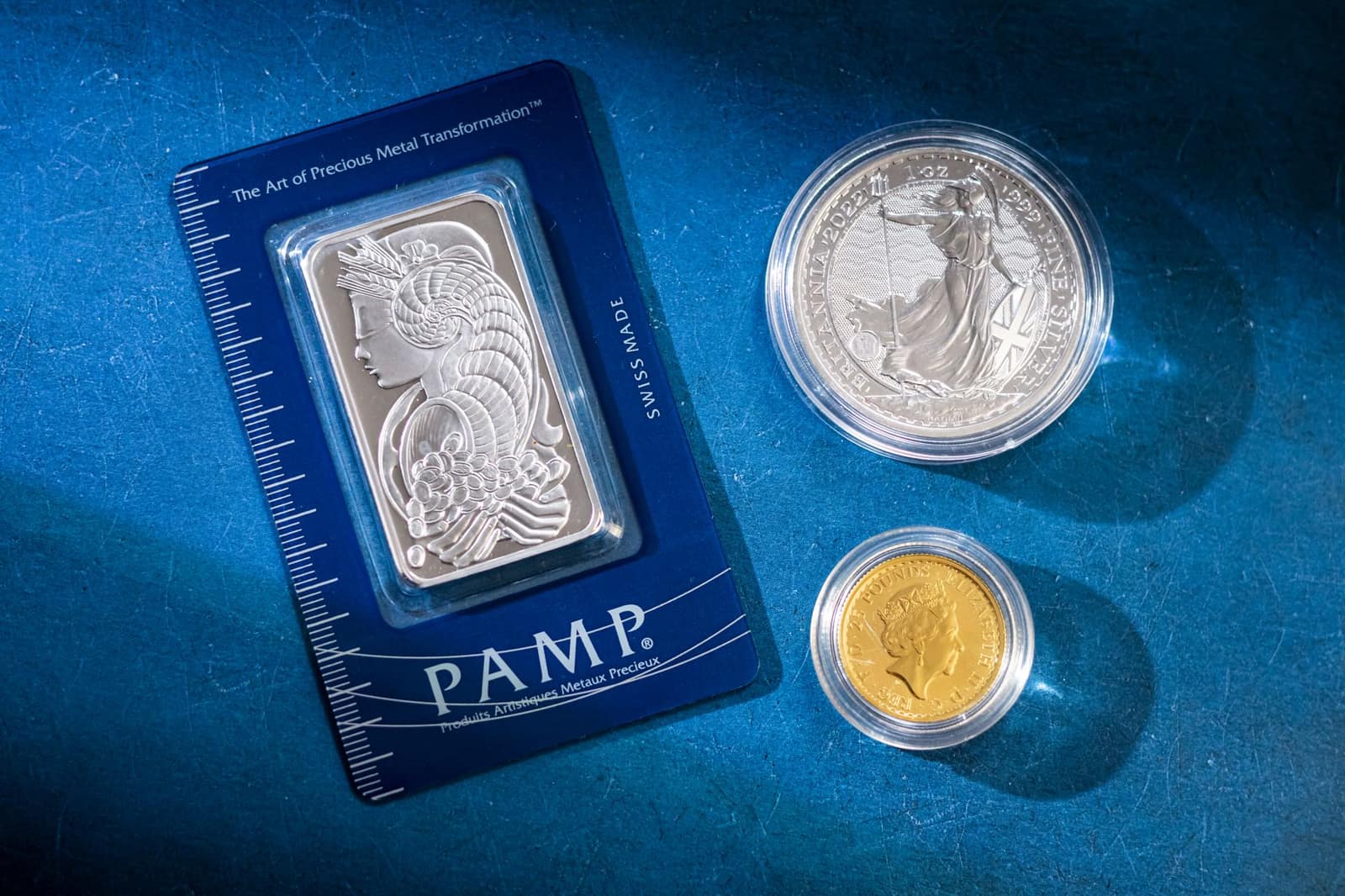 A silver bar and coins displayed on a blue surface