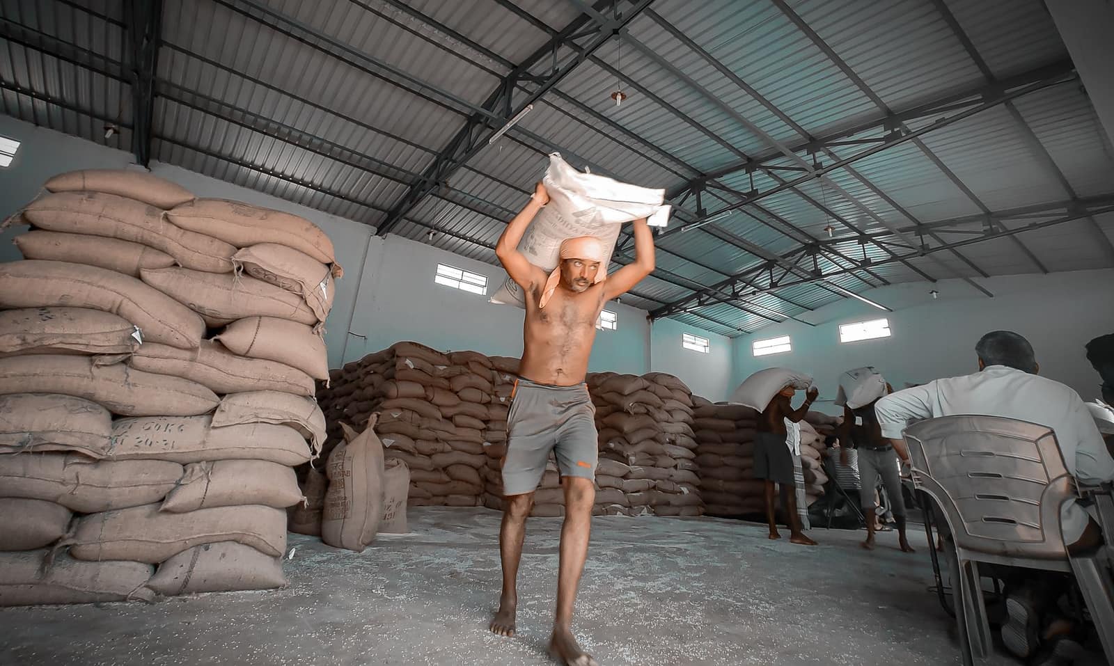 Workers in a warehouse carrying sacks of flour for packaging