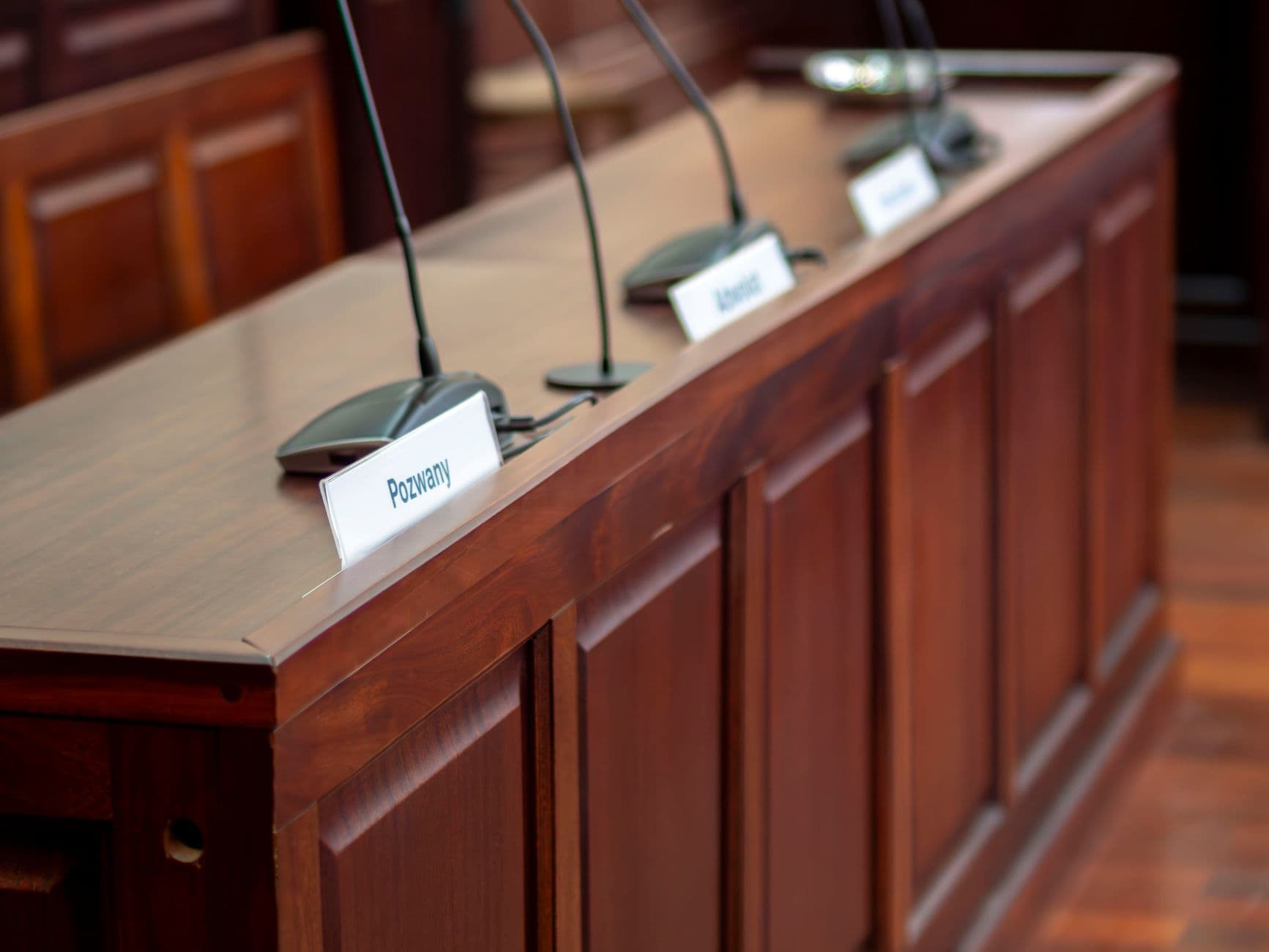 An unoccupied wooden courtroom desk with microphones
