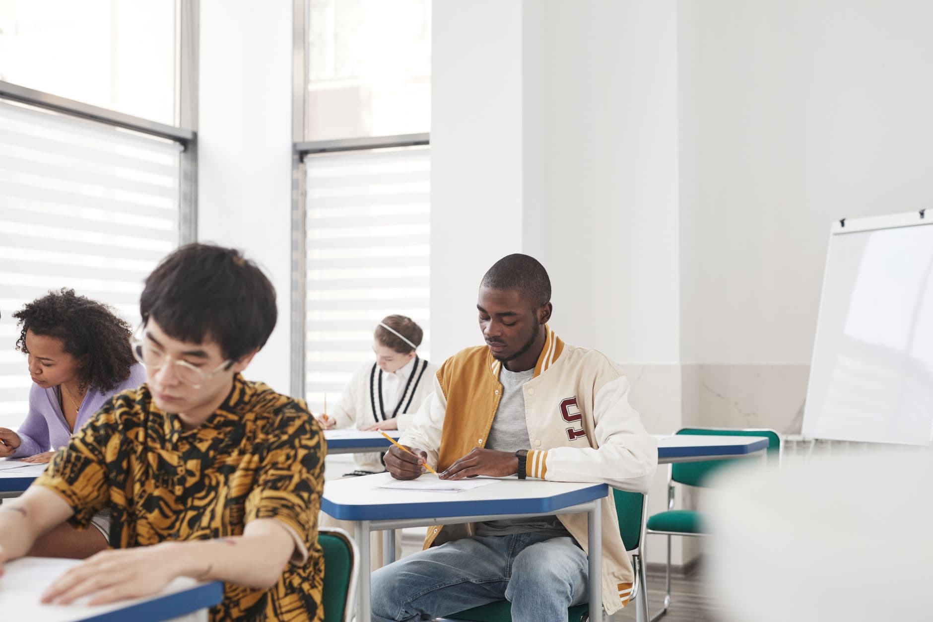 Students sitting at desks inside a classroom taking a written exam