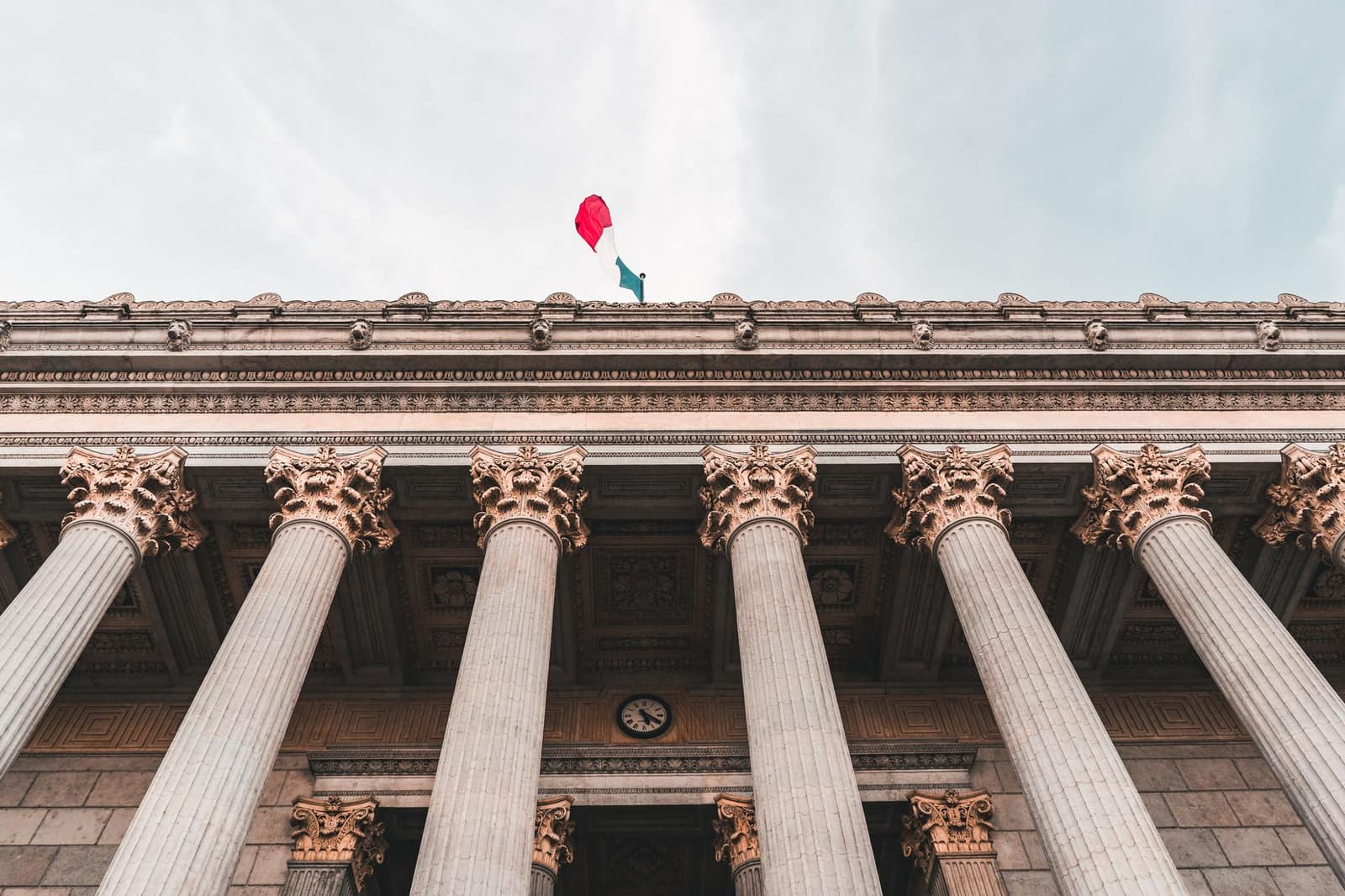 Classical government building facade with columns and a flag against the sky