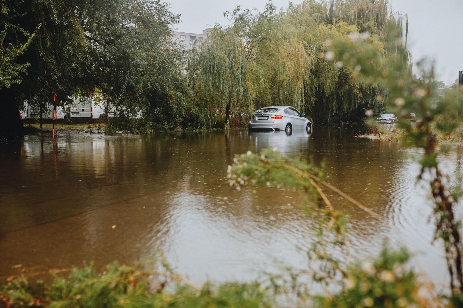 A car navigating a flooded street after heavy rain