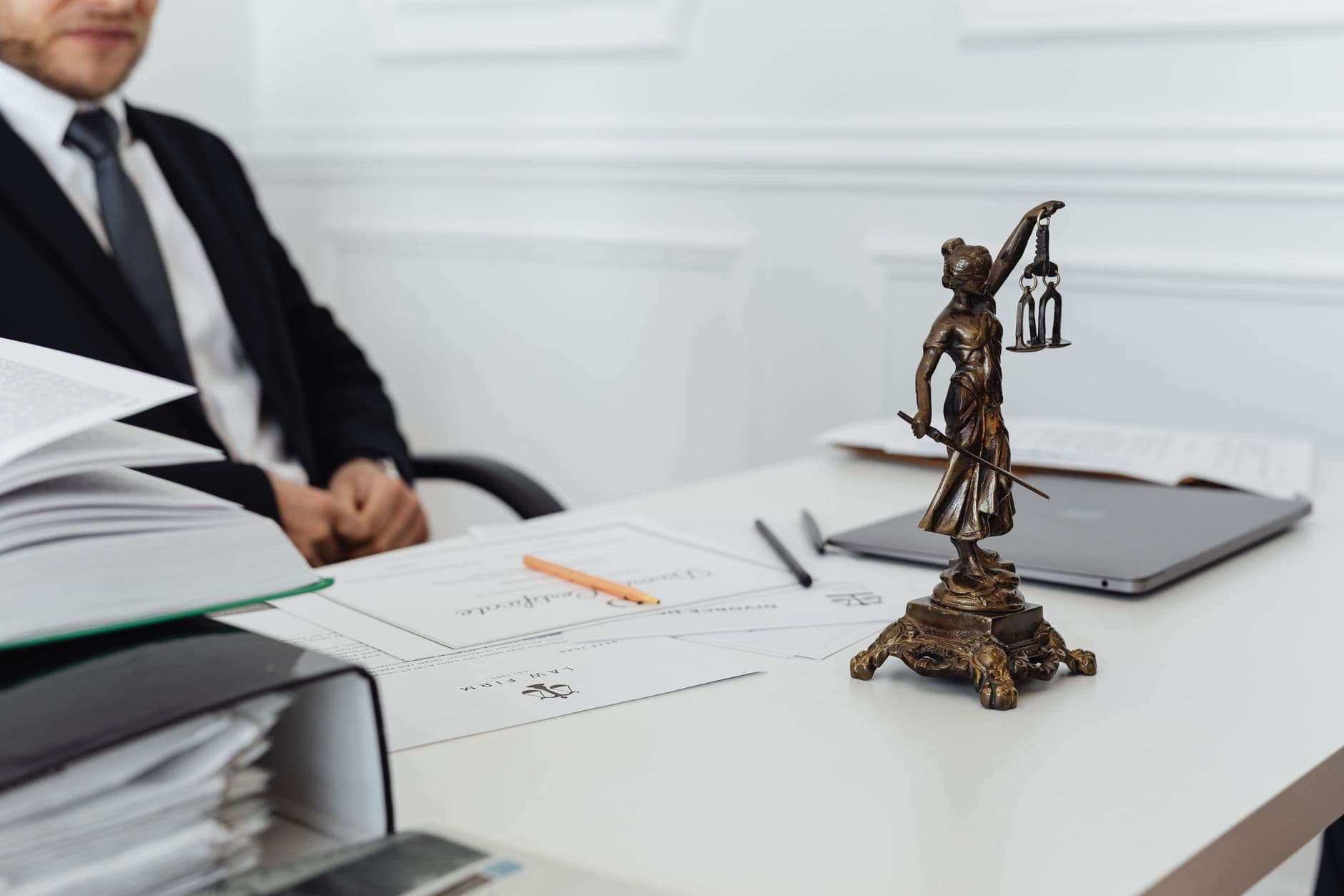 A legal professional's desk with a Lady Justice statue, documents and a laptop