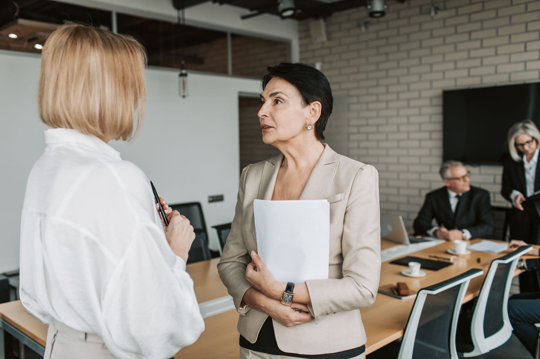 Two businesswomen engaged in conversation during a professional meeting in a modern office