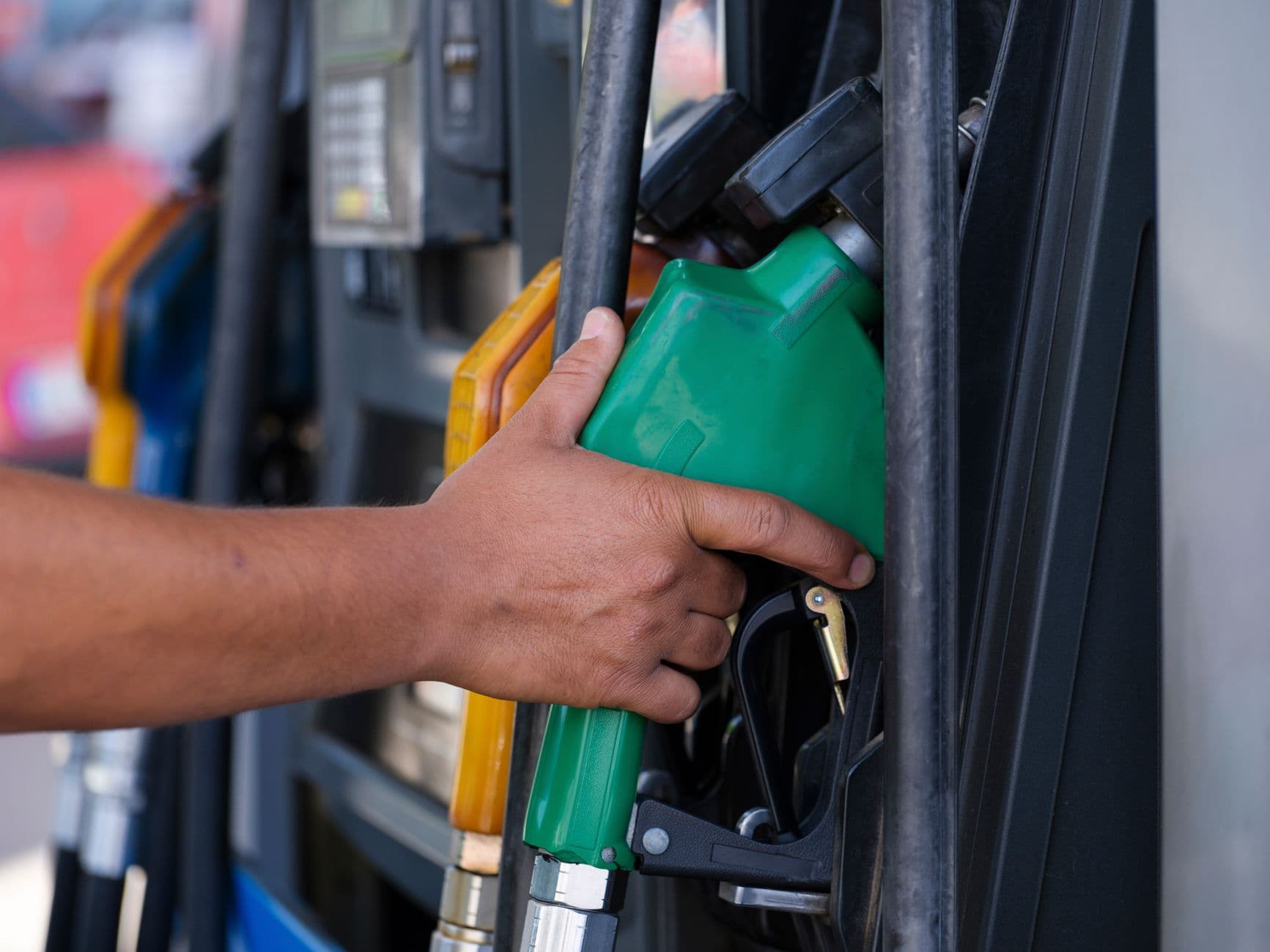Close-up of a hand holding a fuel pump nozzle at a filling station