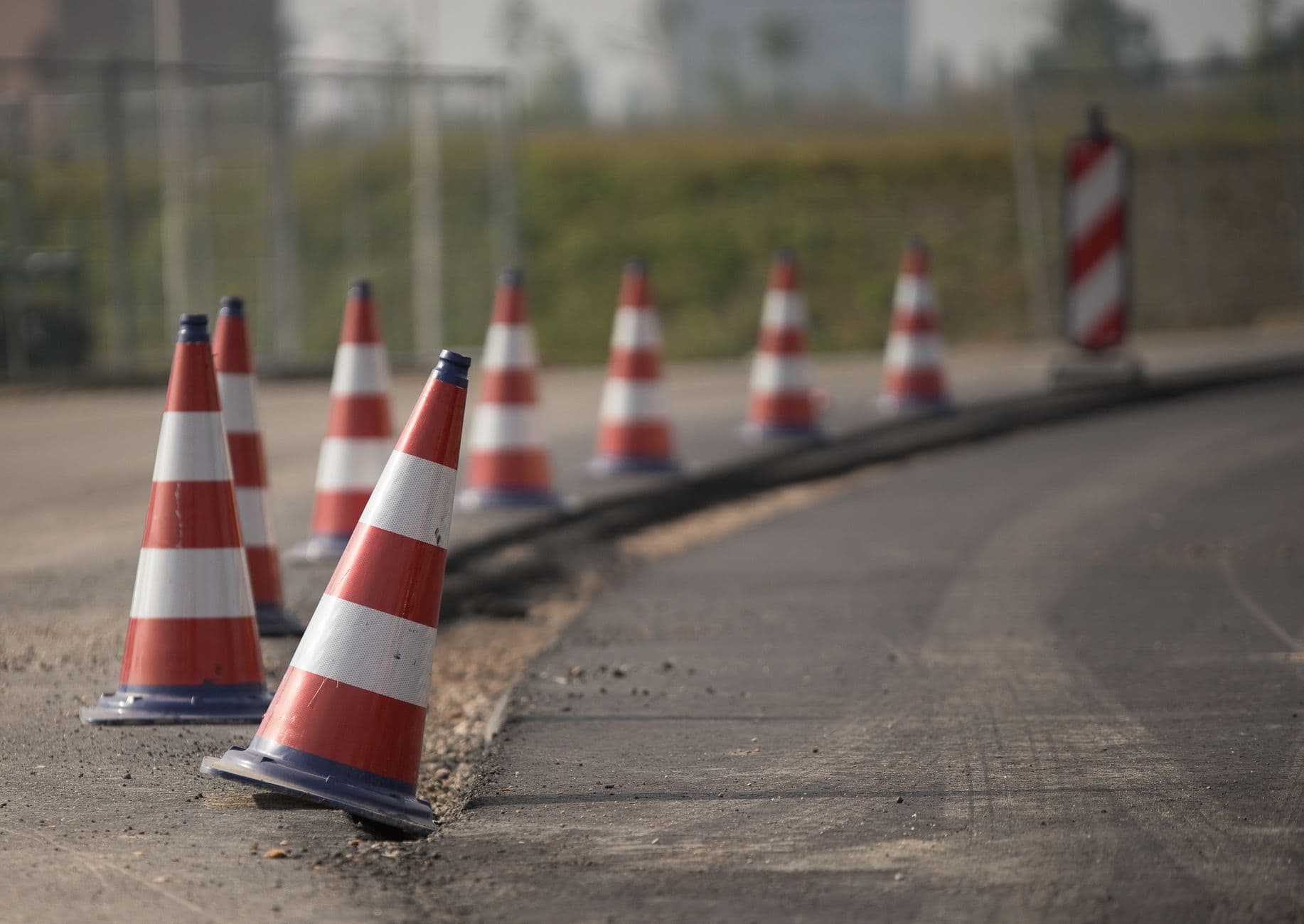 A line of orange and white traffic cones marking a road barrier