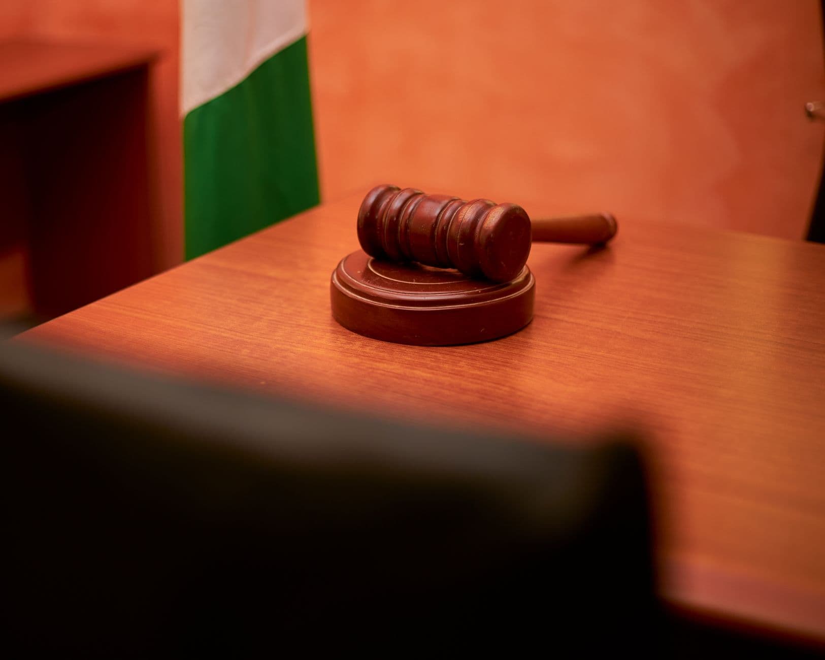 A judicial gavel resting on a courtroom desk